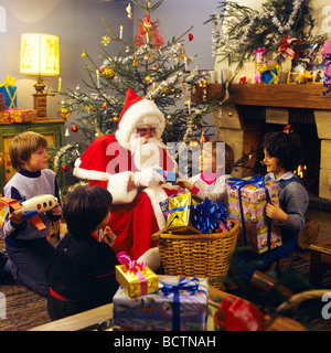 MR SANTA CLAUS GIVING CHRISTMAS PRESENTS TO 4 CHILDREN Stock Photo