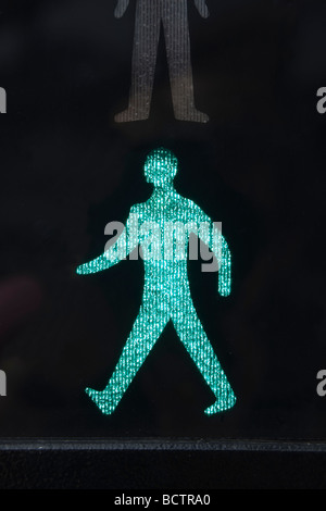 Close up of illuminated walking green man safe to cross road symbol on a pedestrian crossing traffic lights. England UK Britain Stock Photo