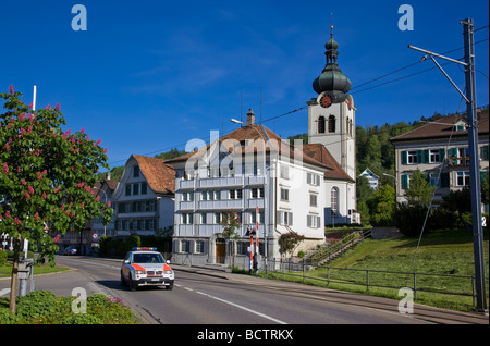 Police car patrolling past Bühler church, Appenzell, Switzerland Stock Photo