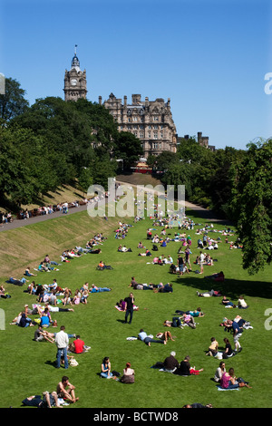 Sunbathers in East Princess Street Gardens in Edinburgh Scotland with Balmoral Hotel in distance Stock Photo