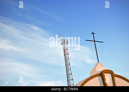 Telecoms antenna near a church cross against the sky Stock Photo