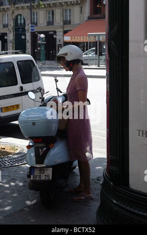 Young French woman making notes in a diary while on the phone on Paris street Stock Photo