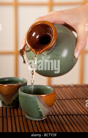 Hand pouring japanese sake in traditional cups Stock Photo