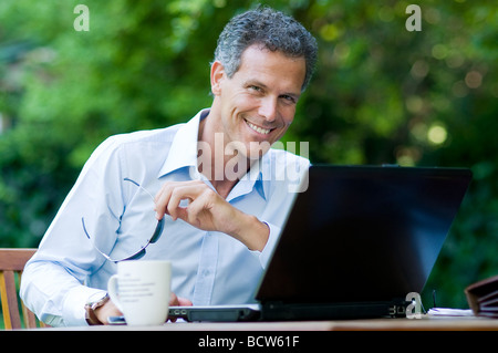 Happy mature businessman looking at camera with a pair of sunglasses in hand Stock Photo