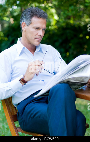 Handsome mature man reading newspaper outdoor with a pair of glasses Stock Photo