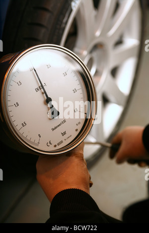 A mechanic checks tyre pressure on a car Stock Photo