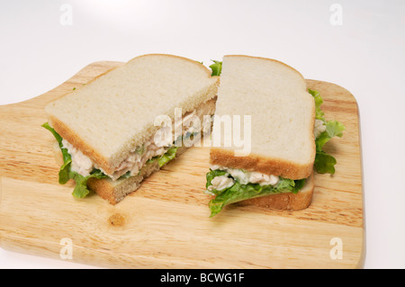 Tuna mayo sandwich on white bread with lettuce on  wood cutting board with white background. Stock Photo