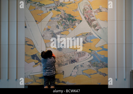 A young boy with his father looking at a ceramic panels mural entitled 'Busy South Wing' by Akira Yamaguchi in Terminal 1 Narita airport Tokyo Japan Stock Photo