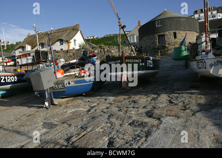 Area of Sennen, England. Fishing boats at Sennen Cove Harbour with the Round House and a thatched cottage in the background. Stock Photo