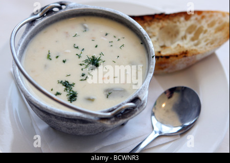 Bowl of Creamy New England Clam Chowder in a metal serving bowl with toasted bread Stock Photo