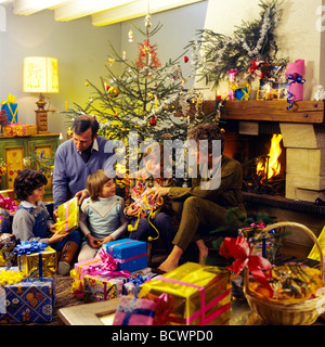 MR COUPLE GIVING CHRISTMAS PRESENTS TO CHILDREN UNDER THE TREE Stock Photo