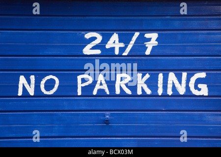 No parking 24/7 sign painted on blue garage door. UK Britain Stock Photo