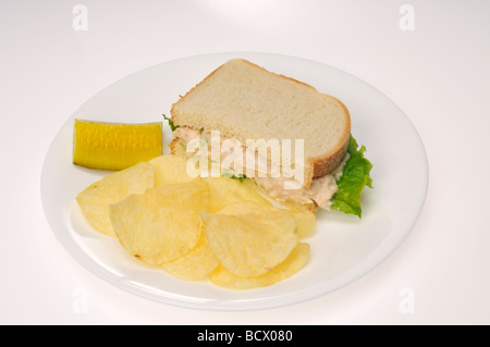 Tuna mayo sandwich with lettuce on white bread with pickle and potato chips Stock Photo