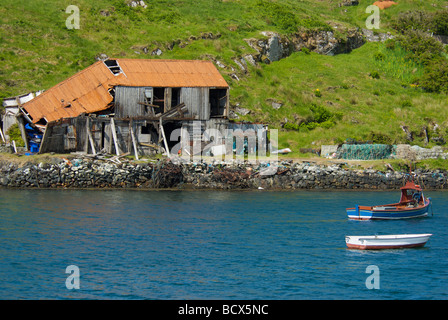 Derelict building with fishing boats in the foreground on the Isle of Scalpay, Western Isles, Outer Hebrides, Scotland Stock Photo