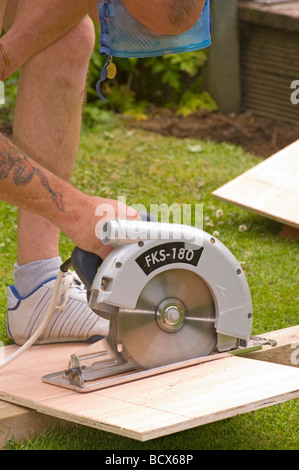 Handyman Cutting a Sheet Of Wood Using a Circular Saw Stock Photo