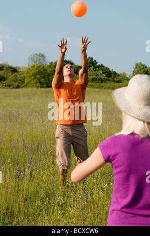 young couple playing volleyball in countryside Stock Photo