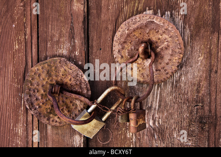 Old wooden door with circular handles and three padlocks Stock Photo