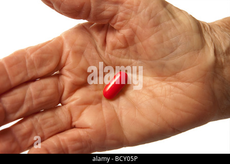 Elderly womans hand holding a red pill Stock Photo