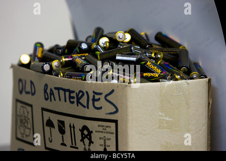 Old batteries for disposal cardboard box full of used Kodak batteries on an office shelf. Stock Photo