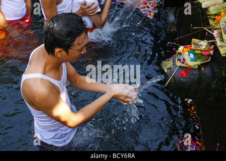 Man at a ceremony at a sacred spring, Tirta Empul at Tampak Siring in the morning light, Bali, Republic of Indonesia, Southeast Stock Photo