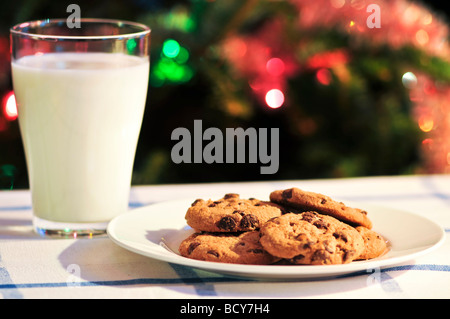 Plate of cookies and glass of milk near Christmas tree Stock Photo