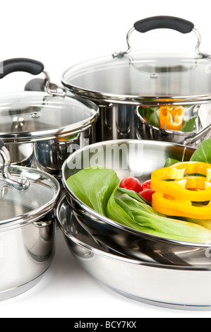 Stainless steel pots and pans isolated on white background with vegetables Stock Photo