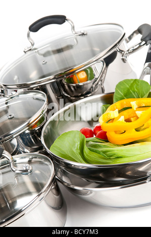 Stainless steel pots and pans isolated on white background with vegetables Stock Photo