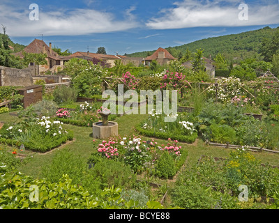 little garden with bloom and blossom and fountain in background houses in Castelfranc in France Stock Photo