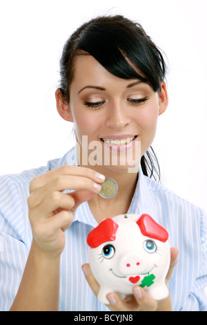 junge Frau steckt Geld in ihr Sparschwein attractive woman banking euro coin in here piggybank Stock Photo