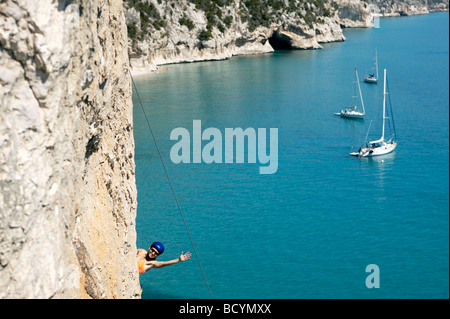 Woman rock climbing, bay in background Stock Photo