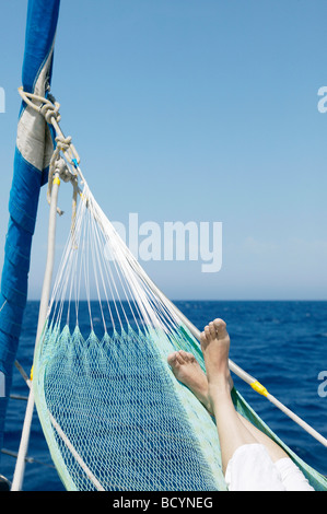 Woman's feet in hammock on sailing boat Stock Photo
