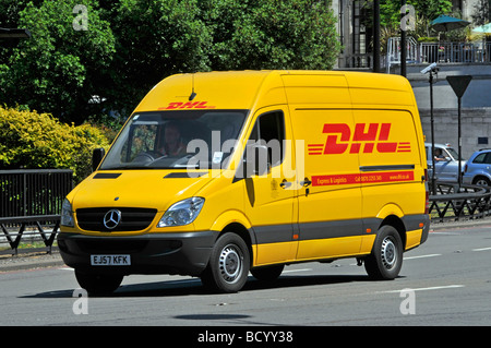 Close up front side view of Mercedes yellow DHL logo brand on parcel delivery van and driver driving along Park Lane Mayfair London England UK Stock Photo