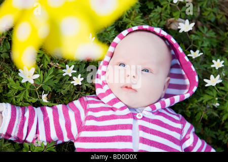 baby lying in grass beneath toy windmill Stock Photo