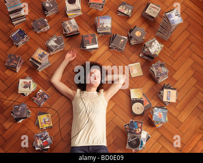 Woman lying on floor, listening to music Stock Photo