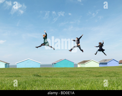 Friends jumping across roofs by seaside Stock Photo