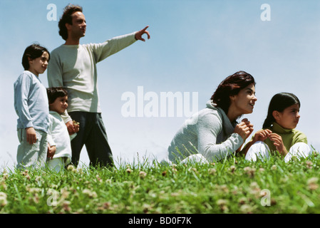 Family together in grassy field enjoying view Stock Photo