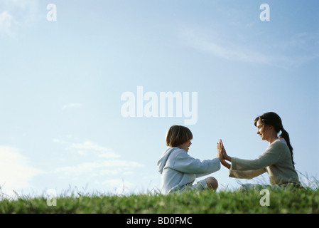 Brother and sister playing clapping game outdoors Stock Photo