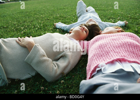 Mother and two children lying together on grass Stock Photo