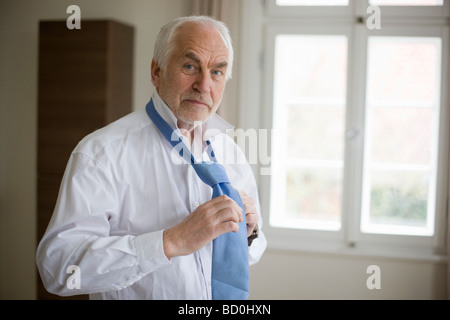 old man putting on tie Stock Photo