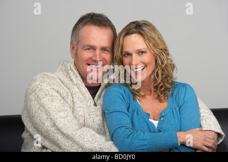 Middle Aged Couple Sitting On Sofa Stock Photo