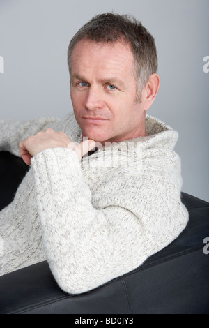 Middle Aged Man Sitting On Sofa Stock Photo