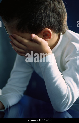 Little boy holding head, upset, covering face Stock Photo