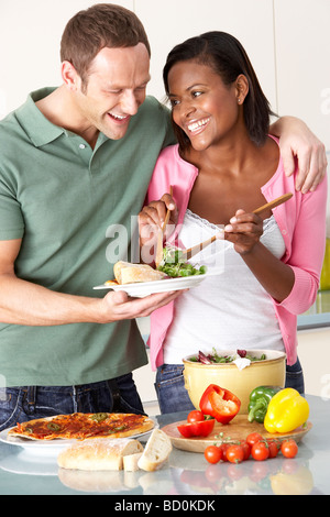 Young Couple Eating Meal In Kitchen Stock Photo