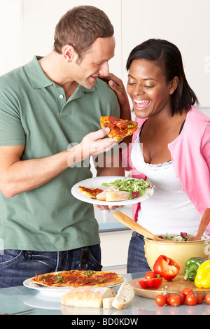 Young Couple Eating Meal In Kitchen Stock Photo
