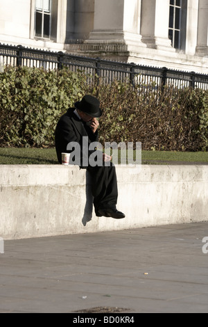 Man in a suit and hat, sitting on a wall Stock Photo