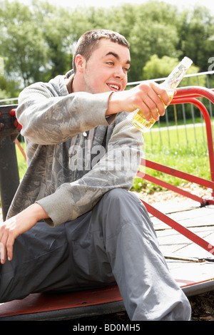 Young Man Sitting In Playground Drinking Beer Stock Photo