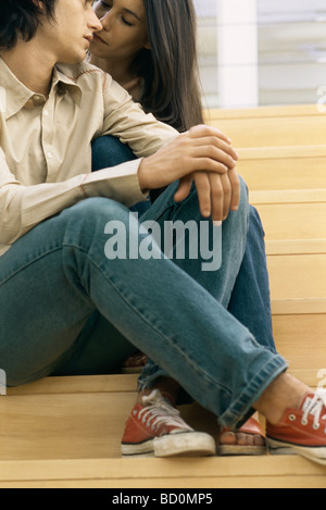 Young couple sitting together on steps, looking into each other's eyes Stock Photo