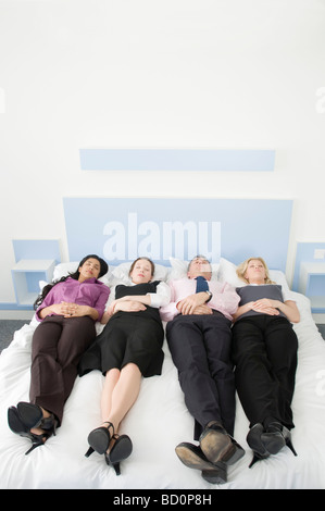 Four business people lying in a bed Stock Photo