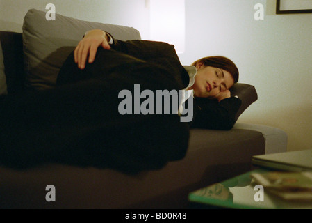 Businesswoman fully clothed sleeping on sofa Stock Photo