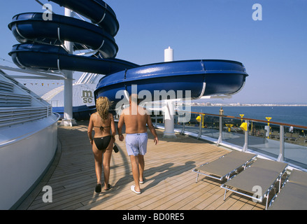 a big waterslide and couple of passengers walking on the sundeck of a cruise ship docked in Palma de Majorca harbour Stock Photo